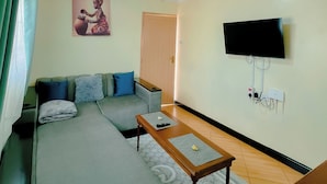 Ein Wohnzimmer mit einer Couch, einem Couchtisch, einem Fernseher und einer Tür.