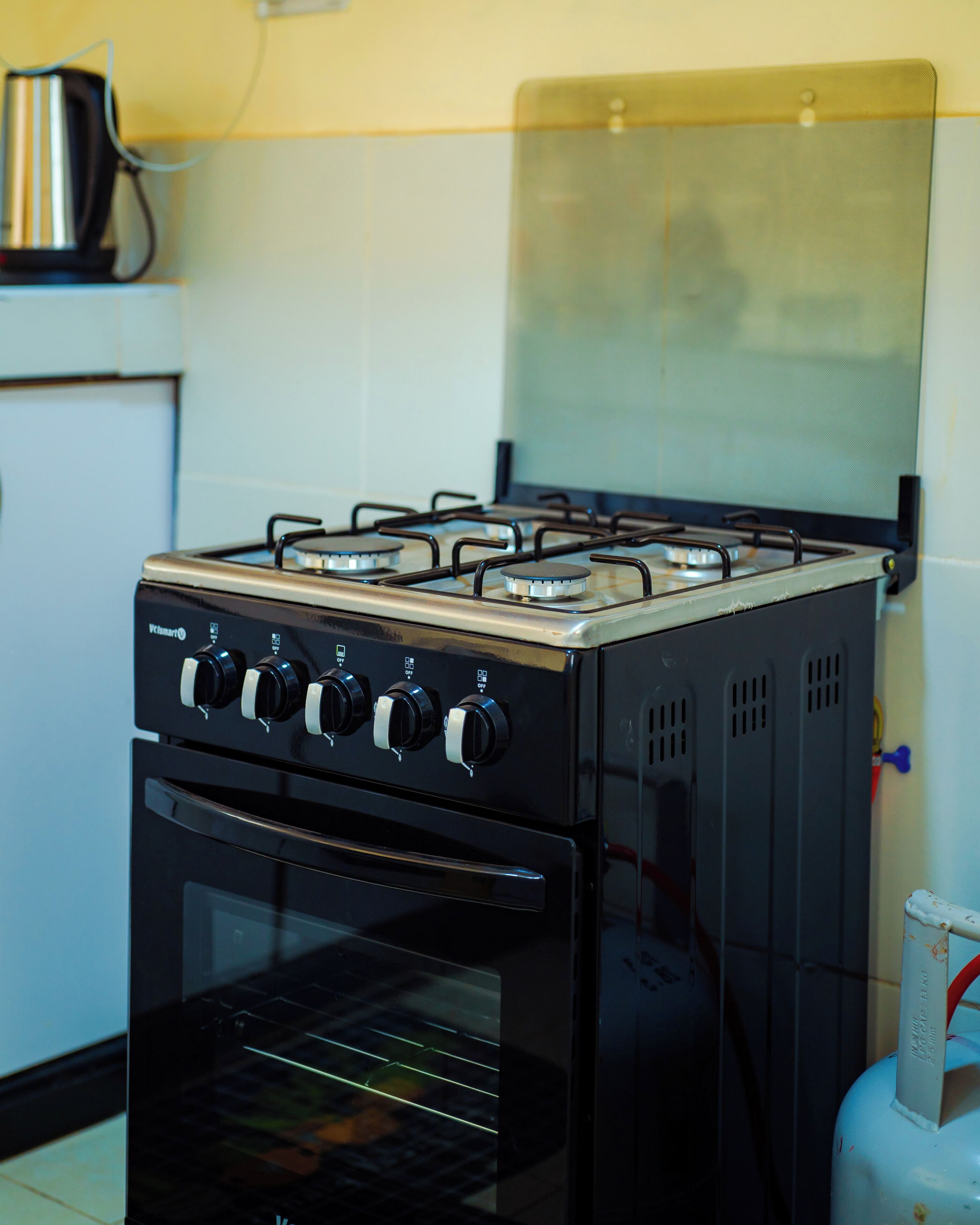 Una cocina con estufa a gas, horno y hervidor sobre la encimera.