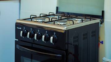 Una cocina con estufa a gas, horno y hervidor sobre la encimera.
