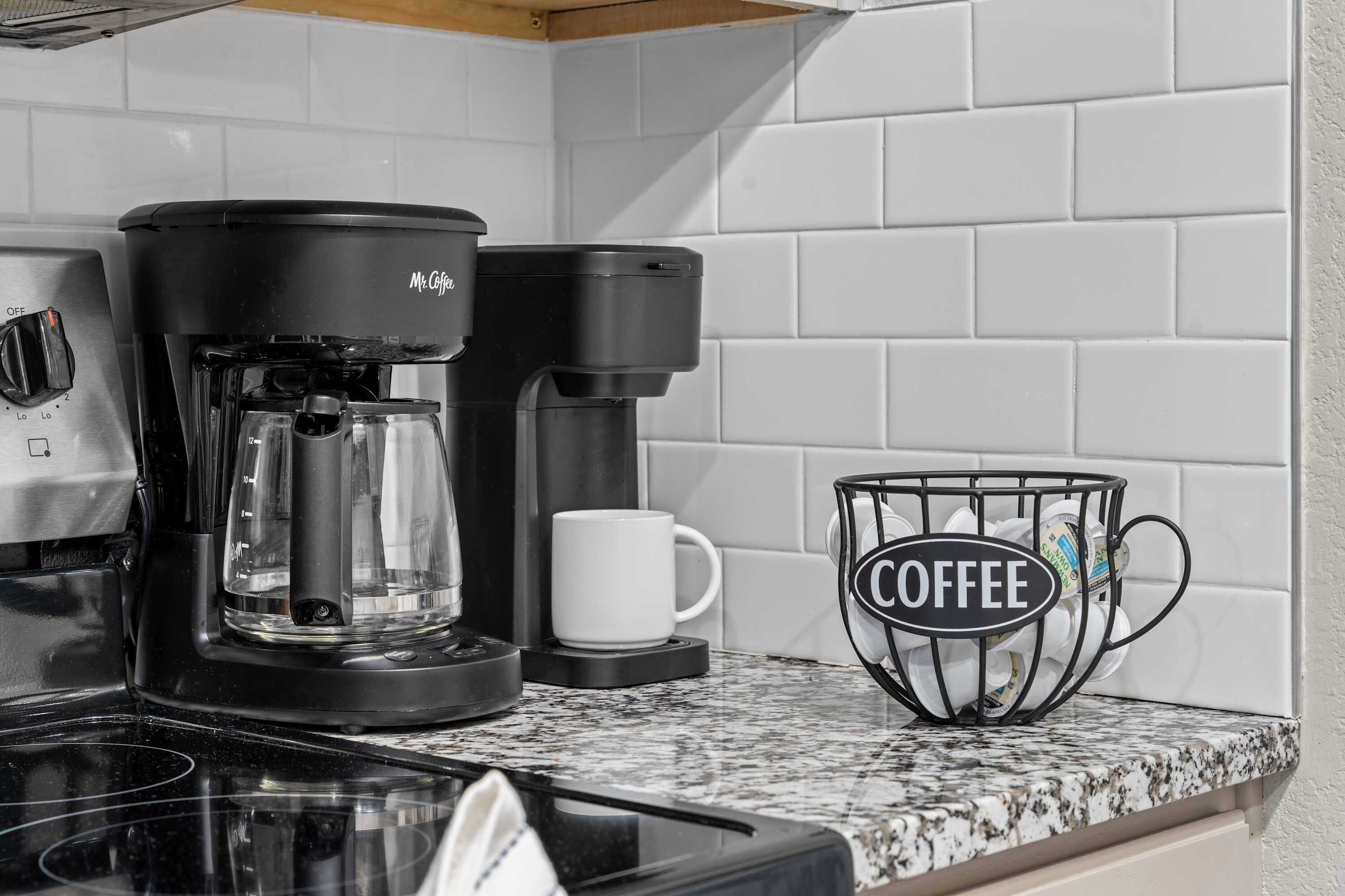 A kitchen with a coffee maker, a coffee pot, and a coffee basket on the counter.