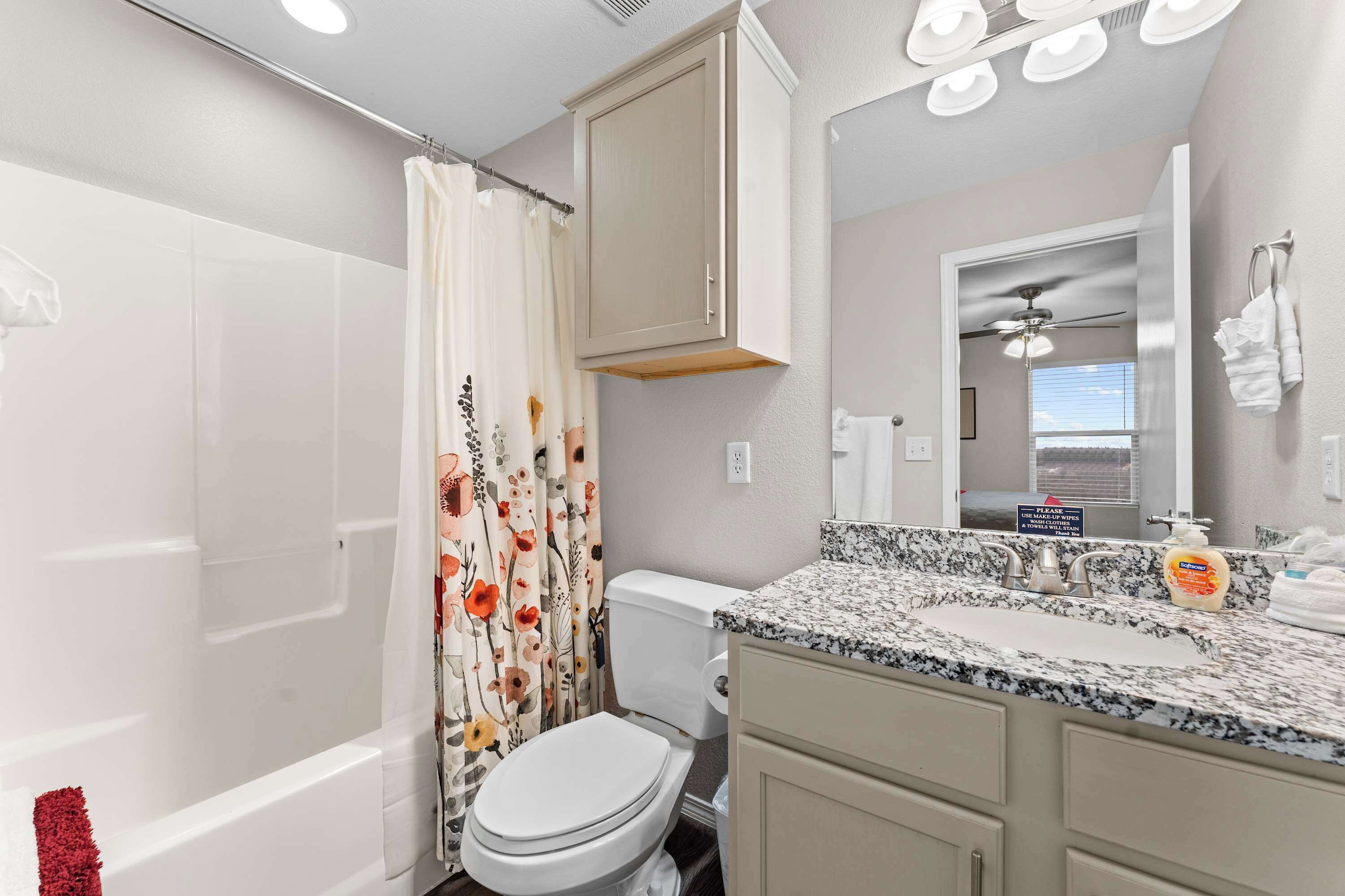 Baño con ducha, inodoro, lavamanos y espejo.