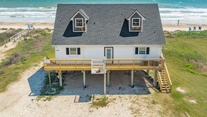 Een huis met twee verdiepingen en een balkon, nabij een strand met uitzicht op de oceaan.