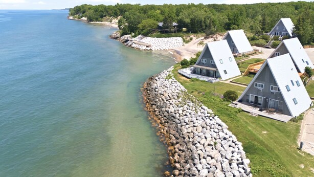 A coastal property with houses, a rocky shoreline, and a clear view of the sea.