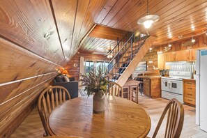 Ein Holzinterieur mit Esstisch, Stühlen, einer Küchenzeile und einer Treppe.