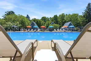 A swimming pool with lounge chairs and umbrellas.