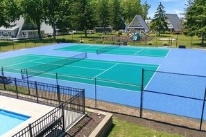 Un court de tennis avec une piscine juste à côté.