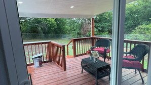 Eine überdachte Terrasse mit Geländer, Eimer und Korbmöbeln.