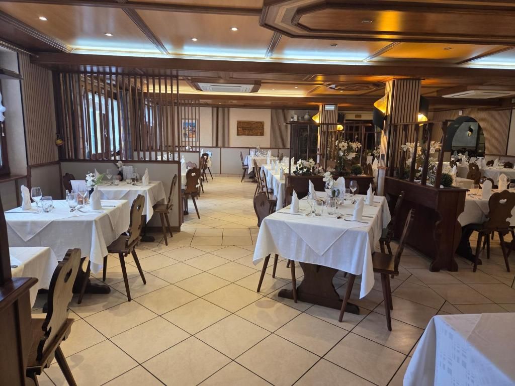 Un restaurante con varias mesas dispuestas para comer, con una decoración clásica que incluye muebles de madera y suelo de baldosas.