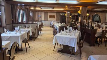 Un restaurante con varias mesas dispuestas para comer, con una decoración clásica que incluye muebles de madera y suelo de baldosas.