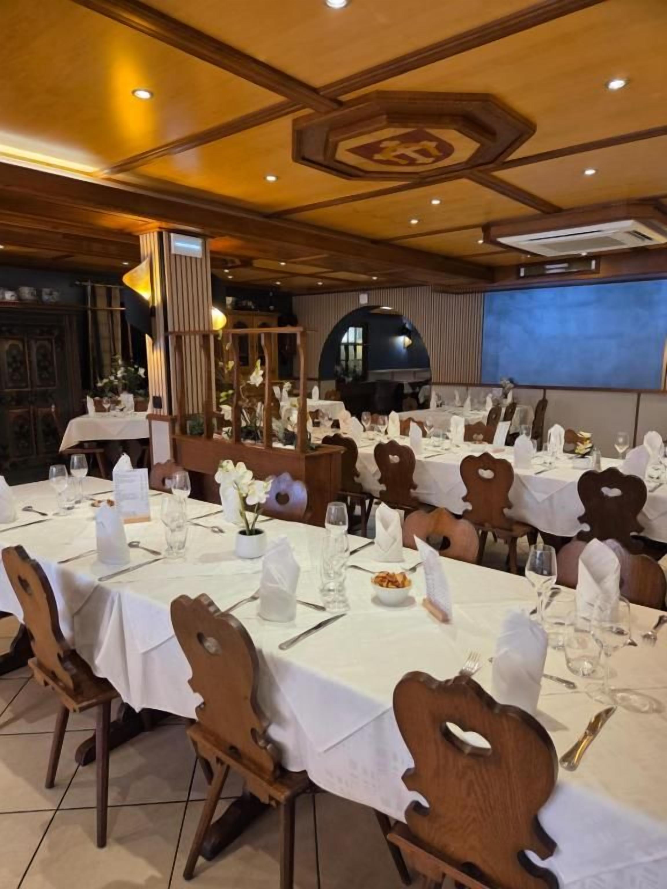 Un comedor con varias mesas dispuestas para el servicio, sillas de madera y un amplio ventanal arqueado.