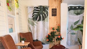 Une pièce comprenant deux fauteuils en cuir marron, une table en bois, une petite table sur laquelle est posée une plante, et un rideau orné d’un motif de feuilles.