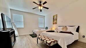 A bedroom with a bed, a desk, a chair, and a ceiling fan. - Big Beautiful BOLD (Grand Prairie)