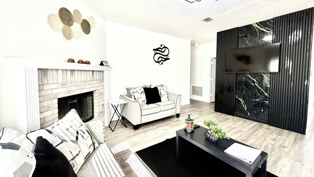 A modern living room with a fireplace, a sofa, a coffee table, and a decorative wall piece. - Big Beautiful BOLD (Grand Prairie)