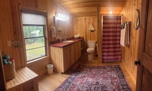 A wooden cabin bathroom with a sink, toilet, and shower curtain. - Adelaide
Cozy Creekside Cottage (Murrells Inlet)