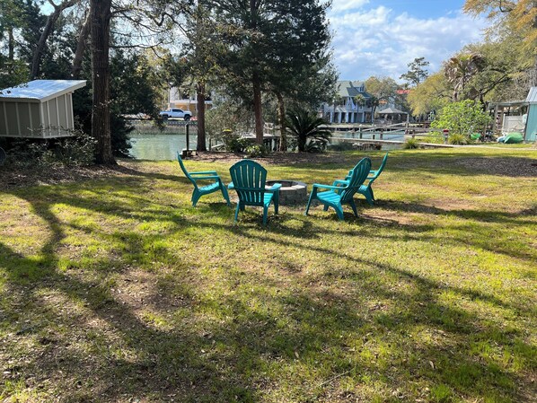 A grassy outdoor area with a fire pit and four green Adirondack chairs. - Adelaide
Cozy Creekside Cottage (Murrells Inlet)