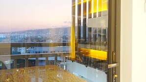 A view through a window with a glass partition, a balcony with a marble table, and a cityscape at dusk. - Pure Simplicity: Sip Coffee Overlooking the Glittering City (Cebu City)