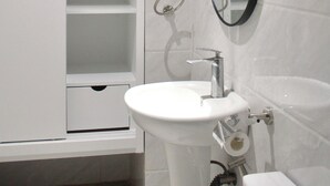 A bathroom with a white sink, a mirror, a red first aid kit, and a cabinet. - Pure Simplicity: Sip Coffee Overlooking the Glittering City (Cebu City)