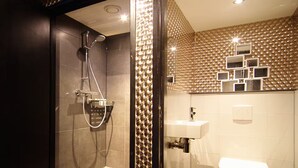 Une salle de bain moderne avec une douche à parois de verre, un lavabo blanc et des toilettes.