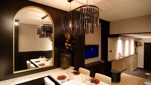 Un espace repas moderne avec une table en marbre, un grand miroir et un luminaire suspendu original.