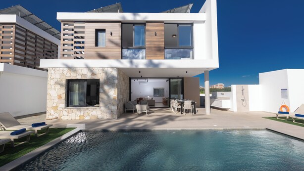 A modern two-story house with a swimming pool, outdoor seating, and a stone facade. - Ayia Napa Orea Villa OR6 (Ayia Napa)