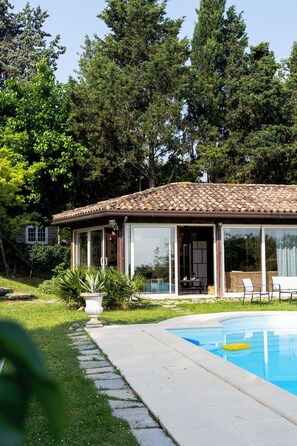 Une maison avec une piscine, entourée d’arbres et d’un jardin.
