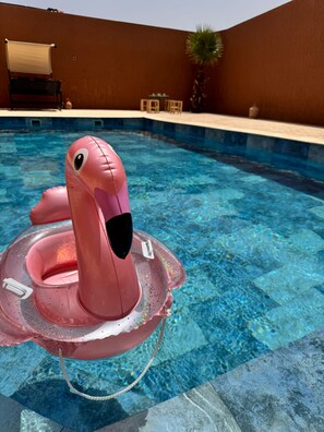 A swimming pool with a pink flamingo float.