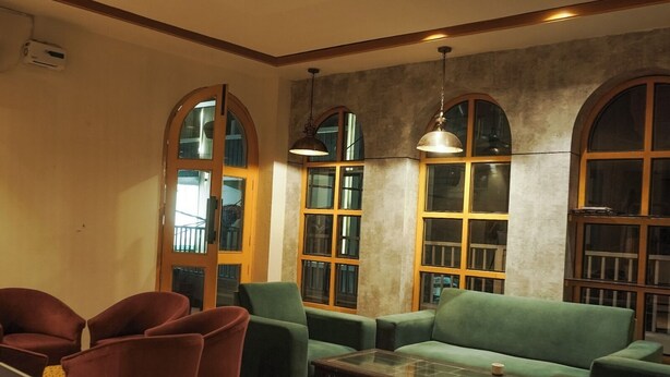 Uma área de estar acolhedora com um sofá verde, poltronas vermelhas e uma mesa de centro de vidro.