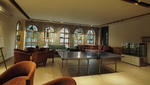 Um quarto espaçoso com mesa de pingue-pongue, assentos confortáveis e amplas janelas em arco.