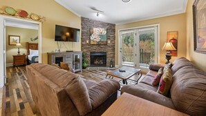 Una sala de estar con chimenea, sofás de cuero, un televisor de pantalla plana y un comedor.