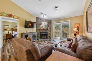 Ein Wohnzimmer mit Kamin, Ledersofas, einem Flachbildfernseher und einem Essbereich.