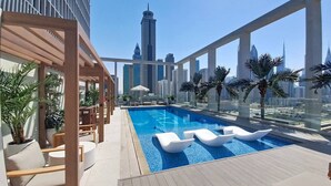 Una piscina sul tetto con lettini, una pergola e palme.