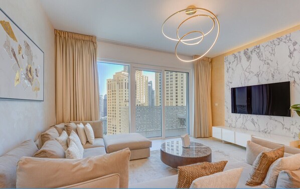A modern living room with a sofa set, a coffee table, and a TV mounted on the wall. - Upgraded 1 Bedroom l JBR Beach l Private Beach (Dubai)