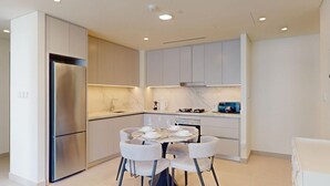 Eine moderne Küche mit einem eingebauten Kühlschrank, einem Esstisch mit Stühlen und einer Mikrowelle auf der Arbeitsplatte.