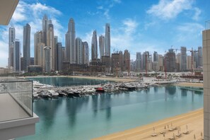 A marina with boats, a beach, and a city skyline with tall buildings. - Perfect 1 Bed l City Skyline Views l Coastal Haven (Emaar Beachfront)