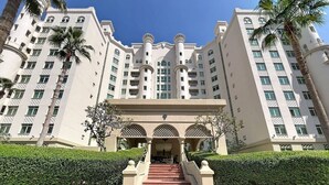 A multi-story hotel with a central staircase, palm trees, and a clear sky. - Chic 2 Bed l Sea Views l Palm Jumeirah Retreat (Palm Jumeirah)