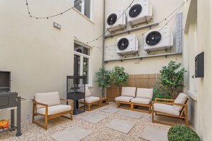An outdoor seating area with four wooden chairs and a table, surrounded by pebbles and potted plants. - Vandenbranden Suites (Brussels)