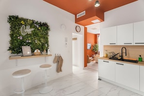 Una cocina moderna con armarios blancos, un jardín de hierbas integrado, un reloj y una zona de bar con taburetes.