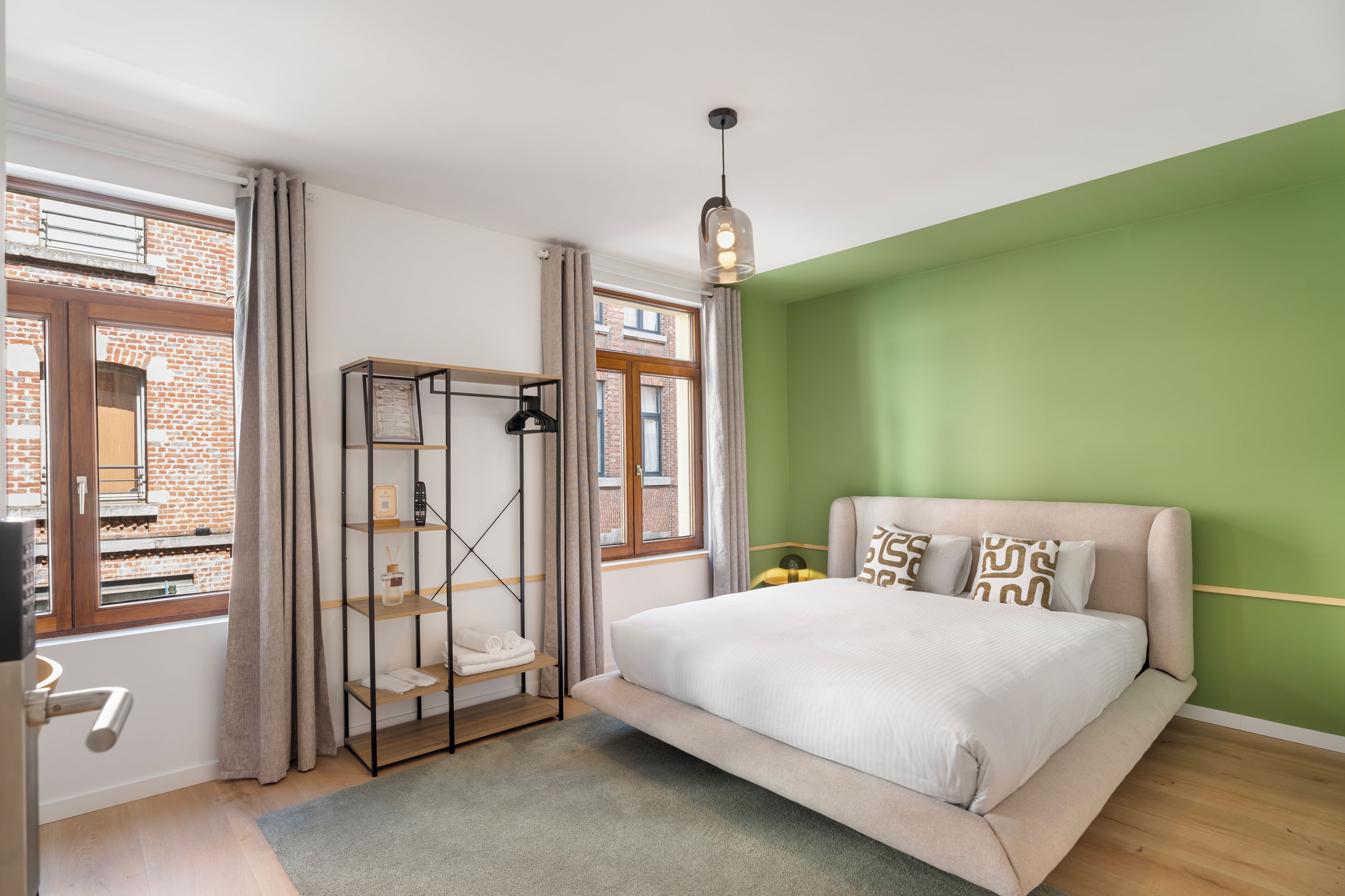 Une chambre avec un lit, une étagère, une fenêtre et un mur vert.