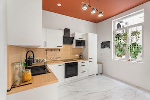 A modern kitchen with white cabinetry, a wooden countertop, and a view of greenery through a window. - Vandenbranden Suites (Brussels)