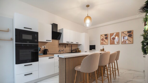 A modern kitchen with a built-in oven, microwave, and bar area with stools.