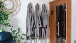 A room with a blue chair, a wall-mounted rack with gray towels, a wooden door, and a plant.