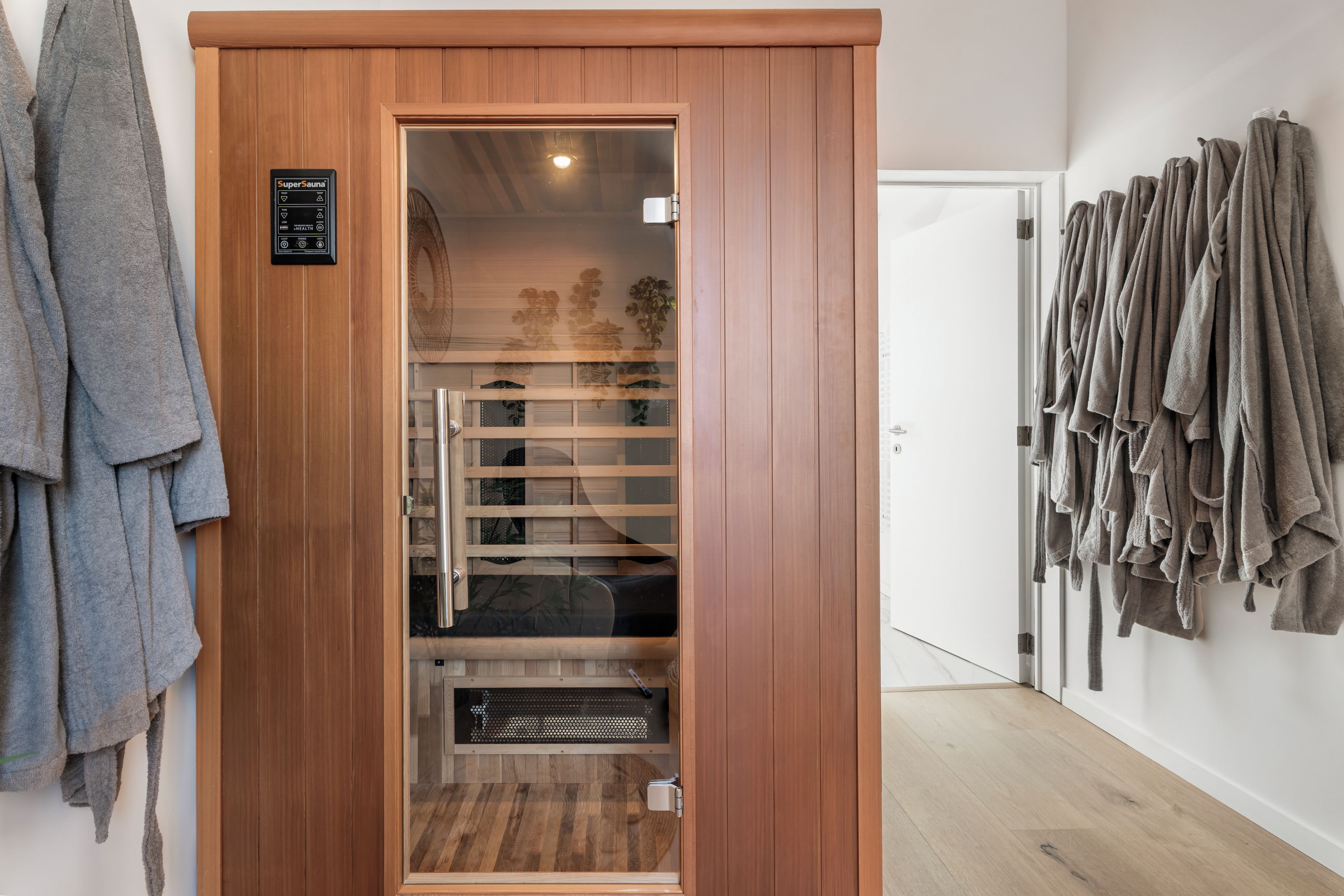 Un sauna avec une porte en bois, un panneau de commande et un porte-serviettes.