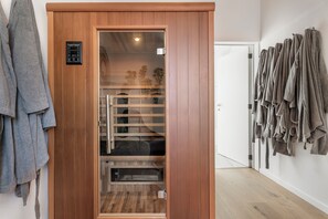 A sauna room with a wooden door, a control panel, and a towel rack. - Vandenbranden Suites (Brussels)