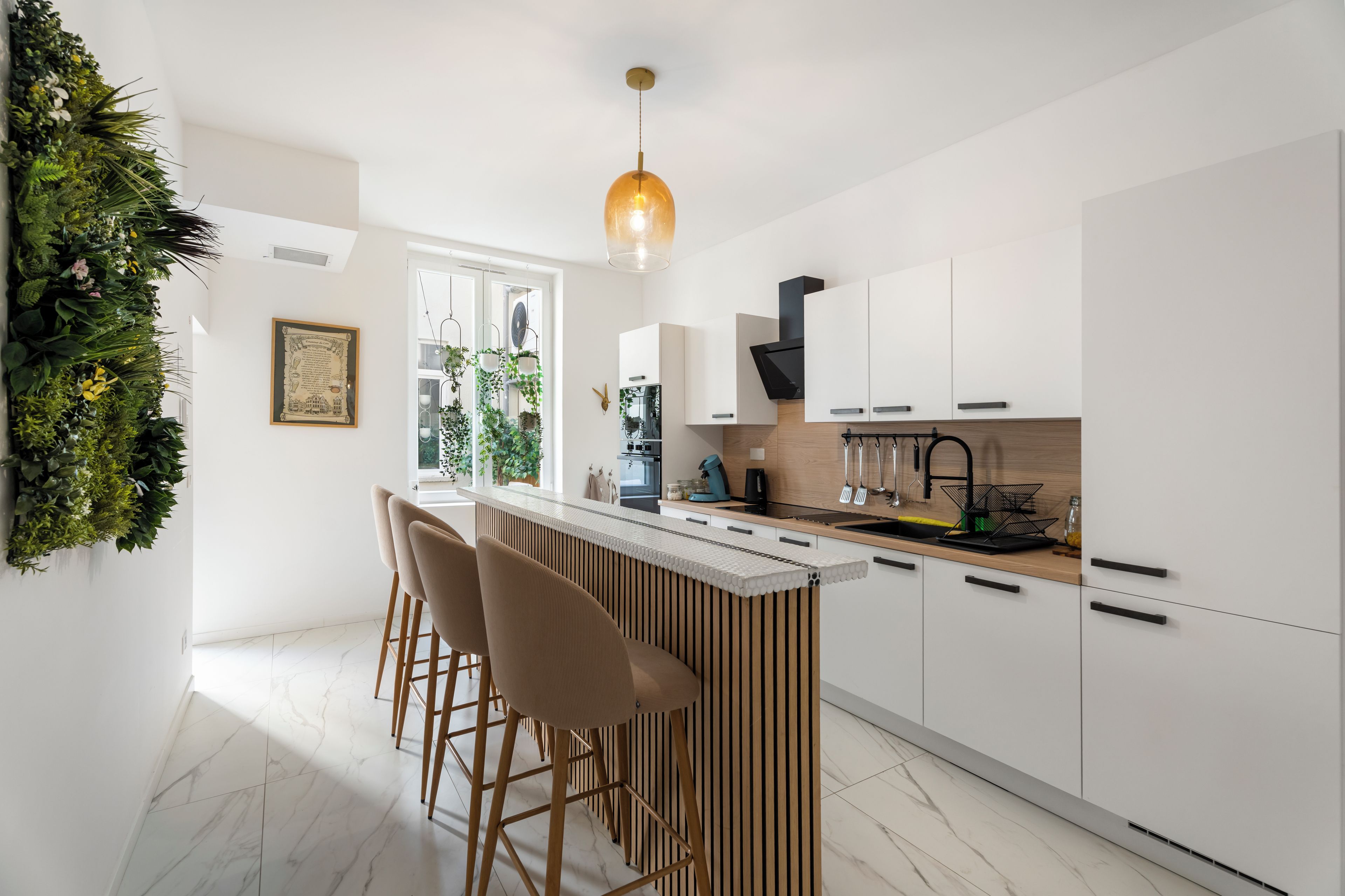 Een moderne keuken met witte kasten, een bar met krukken en een hangende lamp.
