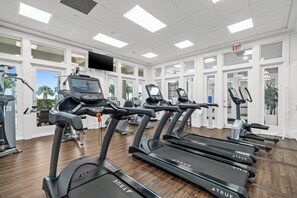A gym with multiple treadmills, exercise bikes, and a television screen displaying workout videos. - Beach Club Avalon 206 K/Q/ Tw-Tw Bunk/SS Sleeps 8 - Beach View- Pools (Gulf Shores)