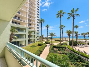 A hotel with multiple balconies, a well-maintained garden with palm trees, and a view of the beach. - Beach Club Avalon 206 K/Q/ Tw-Tw Bunk/SS Sleeps 8 - Beach View- Pools (Gulf Shores)