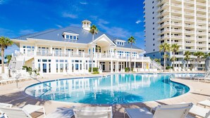 A large swimming pool with white lounge chairs, a grand building with balconies, and palm trees. - Beach Club Avalon 206 K/Q/ Tw-Tw Bunk/SS Sleeps 8 - Beach View- Pools (Gulf Shores)