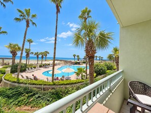 A pool area with lounge chairs and umbrellas, surrounded by palm trees, with a view of the beach and ocean. - Beach Club Avalon 206 K/Q/ Tw-Tw Bunk/SS Sleeps 8 - Beach View- Pools (Gulf Shores)