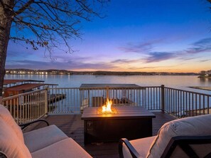 Eine Terrasse mit Feuerstelle, Sitzgelegenheiten im Freien und Blick auf ein Gewässer.