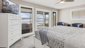 A bedroom with a bed, a dresser, a television, a ceiling fan, and a balcony with a view. - Outdoor Dream Lakefront Home w/ Private Dock, 2 Slips & Kayak (Sunrise Beach)